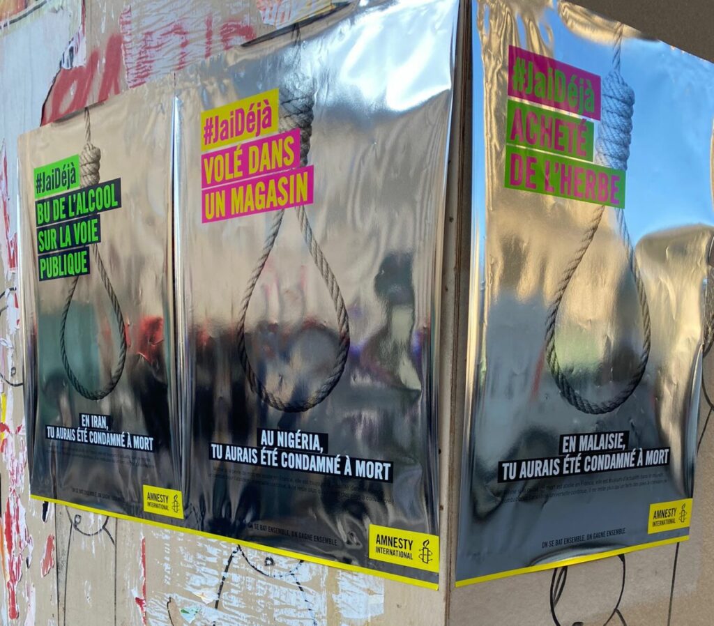Tres carteles plateados pegados en la pared de una calle